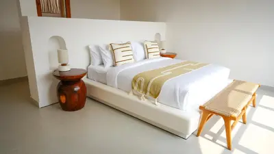 a bedroom with a white bed with pillows and a chair at Miko Villa Seminyak in Seminyak