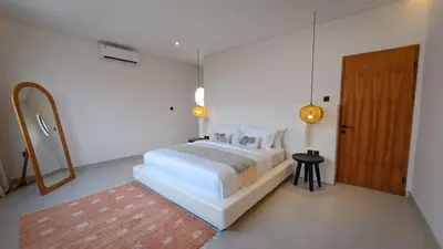 a white bedroom with a bed and a mirror at Miko Villa Seminyak in Seminyak