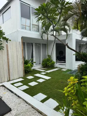 a garden in front of a white house at Villa bella vista in Seminyak