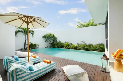 a villa with a swimming pool with a lounge chair and an umbrella at Villa Kalem Canggu by Nakula in Canggu