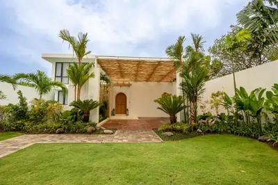 a villa with a lawn and palm trees at Villa Kalem Canggu by Nakula in Canggu