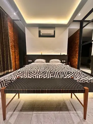 a bedroom with a black and white bed and a bench at The Edge by Anima in Kerobokan