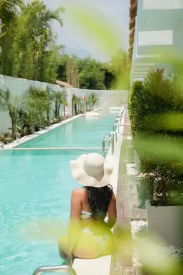 a woman in a hat sitting on a raft in a swimming pool at Baliterraneo Boutique Resort Seminyak in Seminyak