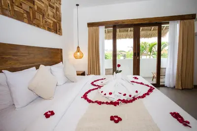 a bedroom with a white bed with red flowers on it at Baliterraneo Boutique Resort Seminyak in Seminyak