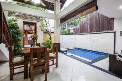 a patio with a table and chairs and a swimming pool at 8-BR Private Pool Legian Villa 5-min Walk to Beach and Shops in Seminyak