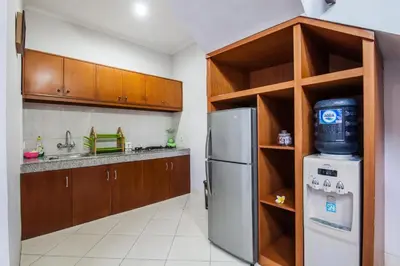 a kitchen with a refrigerator and wooden cabinets at 10-BR Private Pool Legian Villa 5-Min Walk to Beach and Shops in Seminyak