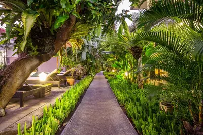 a garden with palm trees and a walkway at 7-BR Private Pool Legian Villa 5-Min Walk to Beach and Shops Bali in Seminyak