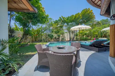 a patio with a table and chairs next to a pool at Villa Lea - 5BR luxury oasis in Seminyak with pool in Kerobokan