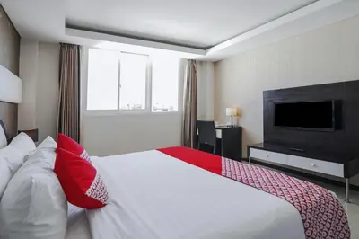 a hotel room with a large bed and a flat screen tv at Townhouse Oak Denpasar at Mahendradatta in Denpasar