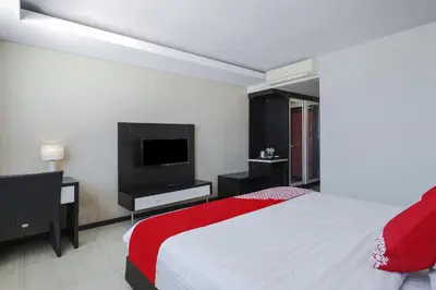 a bedroom with a bed and a flat screen tv at Townhouse Oak Denpasar at Mahendradatta in Denpasar