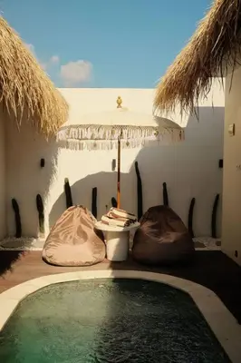 a swimming pool with an umbrella and a table at Amethyst Villa Seminyak in Seminyak