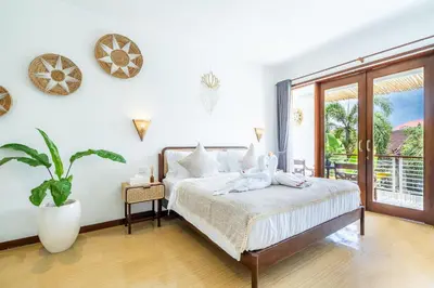 a white bedroom with a bed and a window at Villa Gea by JB Villas in Seminyak