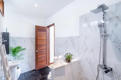 a white bathroom with a shower and a toilet at Villa Gea by JB Villas in Seminyak