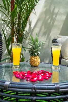 two glasses of orange juice and a pineapple on a table at Villa Gea by JB Villas in Seminyak