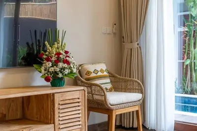 a living room with a chair and a vase of flowers at Arts Cherry Villa Satu Two-Bedroom with Private Pool Kuta in Kerobokan