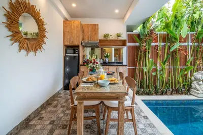 a dining room with a table and chairs and a pool at Arts Cherry Villa Satu Two-Bedroom with Private Pool Kuta in Kerobokan