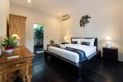 a bedroom with a large bed and a wooden table at Bens Seminyak Villa Two-Bedroom with Private SwimmingPool in Seminyak