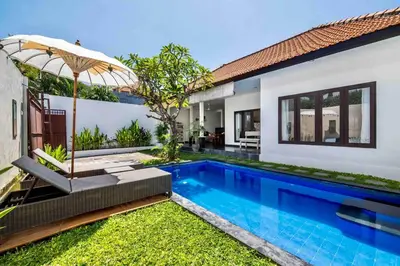 a swimming pool with an umbrella next to a house at Bens Seminyak Villa Two-Bedroom with Private SwimmingPool in Seminyak
