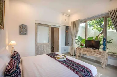 a bedroom with a bed and a tv and a window at Bens Kenanga Villa Three-Bedroom with Private Pool Kuta in Kerobokan