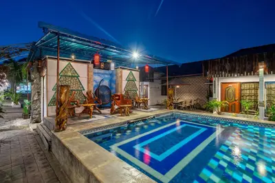 a swimming pool in front of a house at night at Senyum Bali Inn 1BR Sanur in Sanur