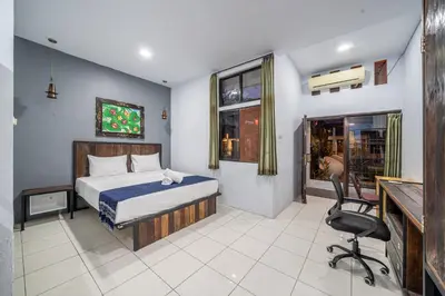 a bedroom with a bed and a desk and a chair at Senyum Bali Inn 1BR Sanur in Sanur