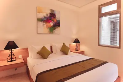 a bedroom with a bed with two lamps and a window at Amaya Residence Jimbaran in Jimbaran