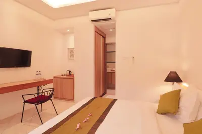 a bedroom with a bed and a desk and a television at Amaya Residence Jimbaran in Jimbaran