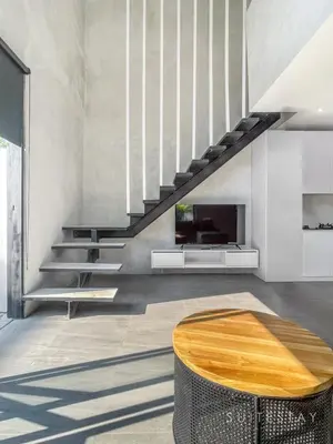 a living room with a wooden table and stairs at Modern Duplex With Stylish Design in Canggu