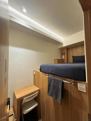 a small room with a bed and a small table at Althia Private Capsule Quarters in Badung