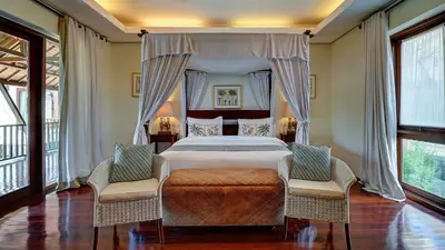 a bedroom with a large bed and two chairs at Casa Evaliza by Elite Havens in Seminyak
