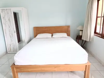 a bed in a bedroom with a wooden bed frame at Bcoss Stay in Jimbaran