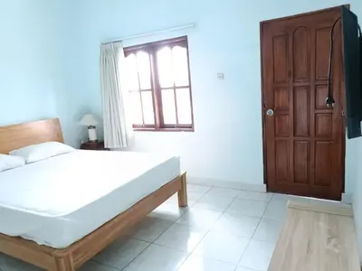 a bedroom with a bed and a wooden door at Bcoss Stay in Jimbaran