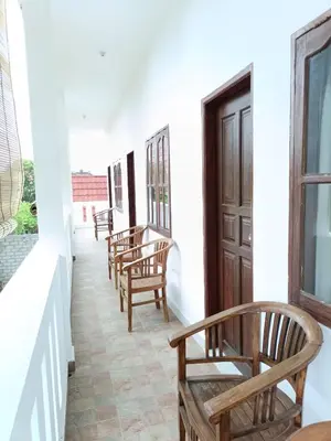 a row of chairs on the porch of a house at Bcoss Stay in Jimbaran
