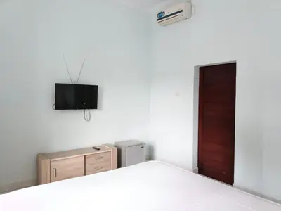 a bedroom with a bed and a tv on the wall at Bcoss Stay in Jimbaran