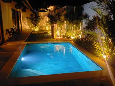 a swimming pool in a backyard at night at Villa La madrina in Kerobokan