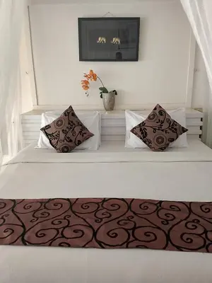 a white bed with two pillows and a vase on it at Privat Pool Villa at Kuta in Kuta
