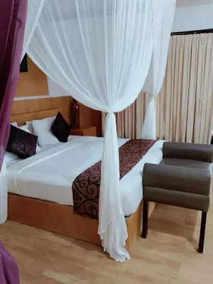 a bedroom with a bed with curtains and a chair at Privat Pool Villa at Kuta in Kuta