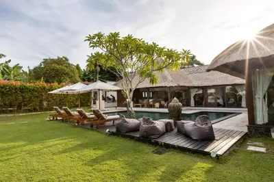 a backyard with a pool and chairs and a house at Palm Merah Villa in Umalas
