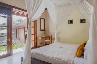 a bedroom with a white canopy bed and a desk at Villa Charlie Seminyak in Badung