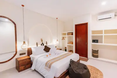 a white bedroom with a large bed and a mirror at Luxury Villa Noah in Kuta