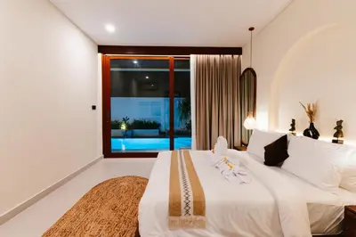 a bedroom with a white bed and a large window at Luxury Villa Noah in Kuta