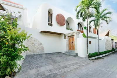 a white house with a door and a palm tree at Luxury Villa Noah in Kuta