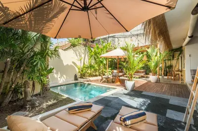 a swimming pool with chairs and an umbrella and a pool at Lovely 1 BR villa walking distance to the beach in Seminyak