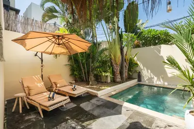 a patio with two chairs and an umbrella next to a pool at Lovely 1 BR villa walking distance to the beach in Seminyak