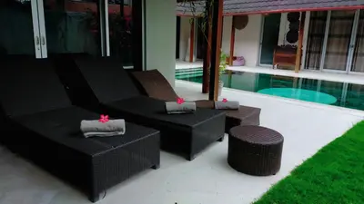 a patio with two wicker chairs and a pool at J & J villa Seminyak in Seminyak