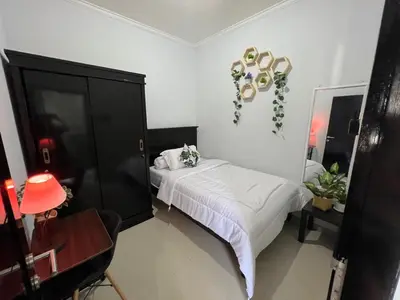 a bedroom with a bed and a black cabinet at Chandra's House in Pesanggaran