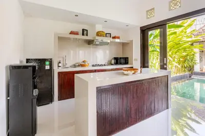 a kitchen with white walls and wooden cabinets and a window at Gemstones Villa in Seminyak