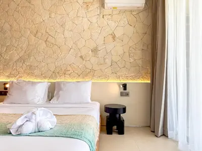 a bedroom with two beds and a stone wall at Saint Cloud Villa Umalas in Canggu