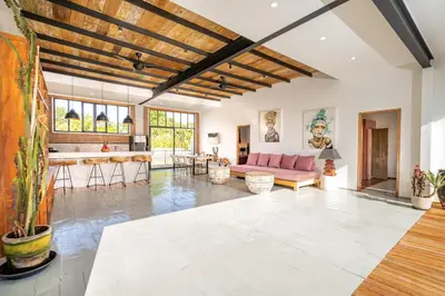 a living room with a pink couch and a kitchen at Villa Anzo by DreamAwayBali in Seminyak