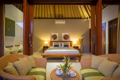 a bedroom with a bed and two wicker chairs at Villa Green Mango 2 Seminyak Bali in Seminyak